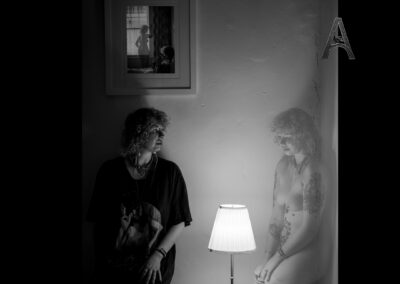 A clothed woman and a nude version of herself share a quiet moment around a single lamp. Neither dominates the space. Neither disappears. The image explores the possibility that self-acceptance is not about choosing one version of ourselves over another, but allowing them to exist together. MUSE: Ferine