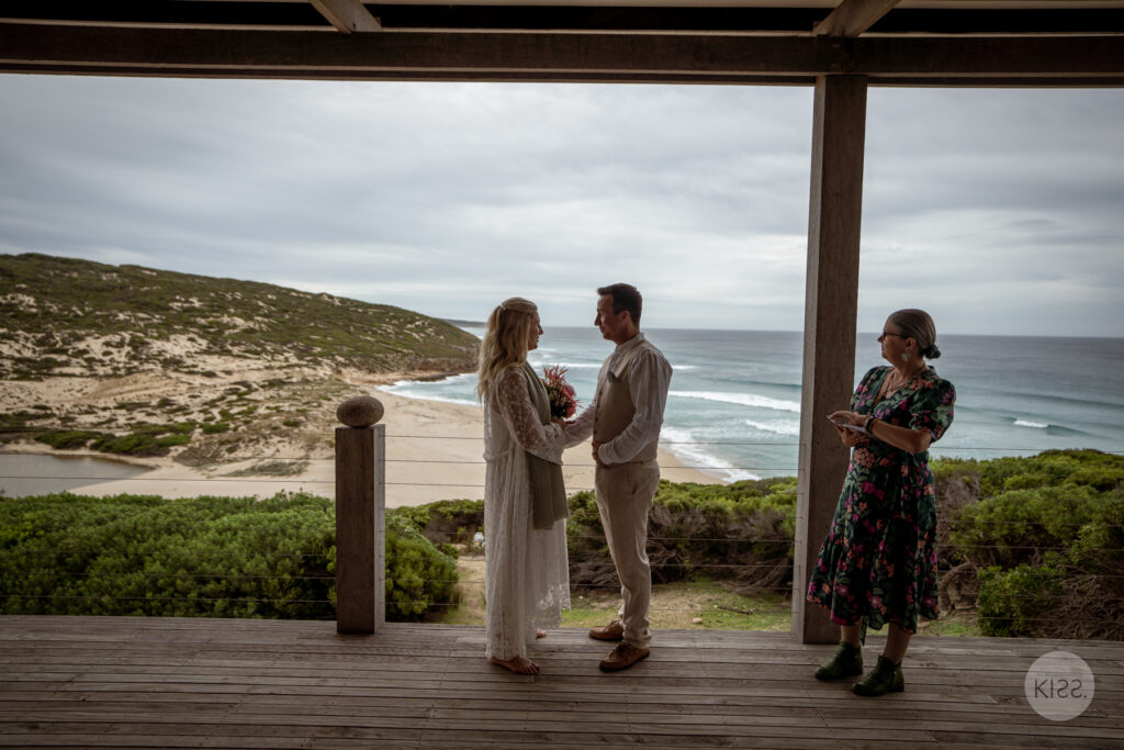 A small wedding ceremony framed by the cottage veranda and coastline