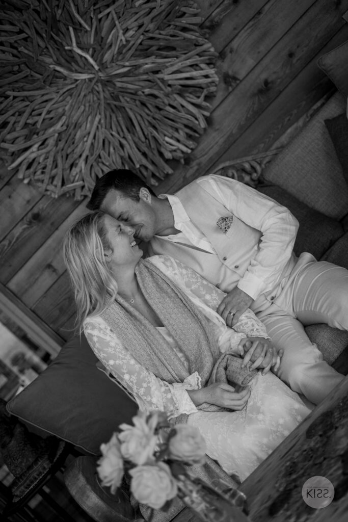 A couple leaning together on a cottage sofa, in black and white