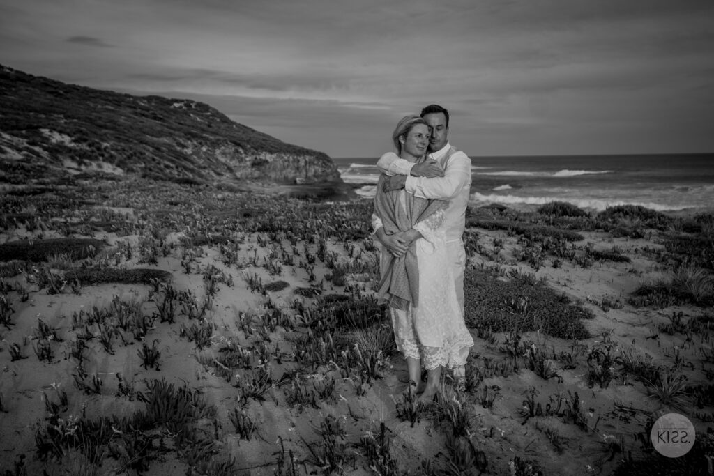 A couple embracing among coastal rocks, in black and white